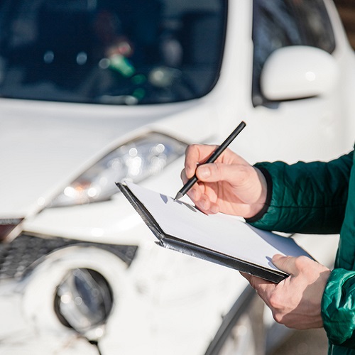 Vehicle owner reviewing a valuation report beside a repaired vehicle