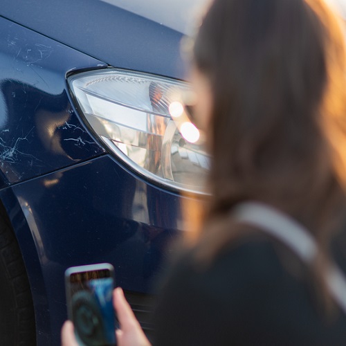 Clean silver car in a driveway with a smartphone on a tripod documenting it